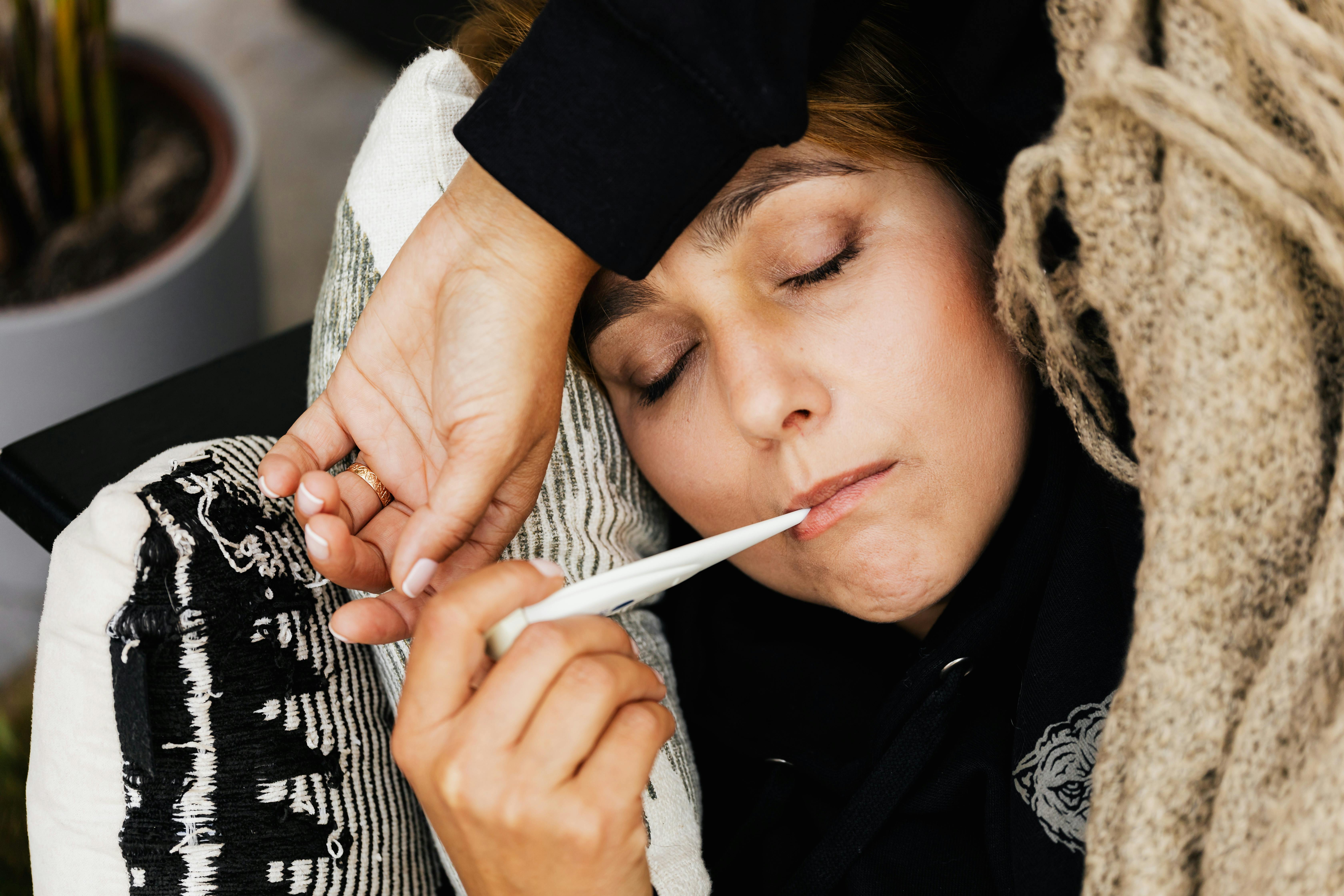 Person mit Thermometer bei Fieber und häufigen Infekten in Deutschland